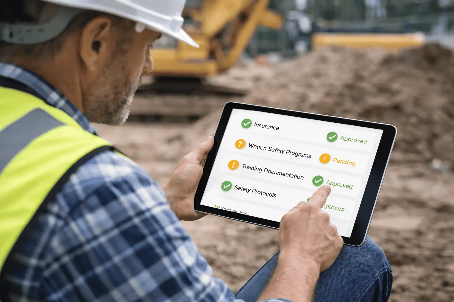 Construction contractor in hard hat reviewing a tablet showing contractor prequalification status โ green approved indicators visible